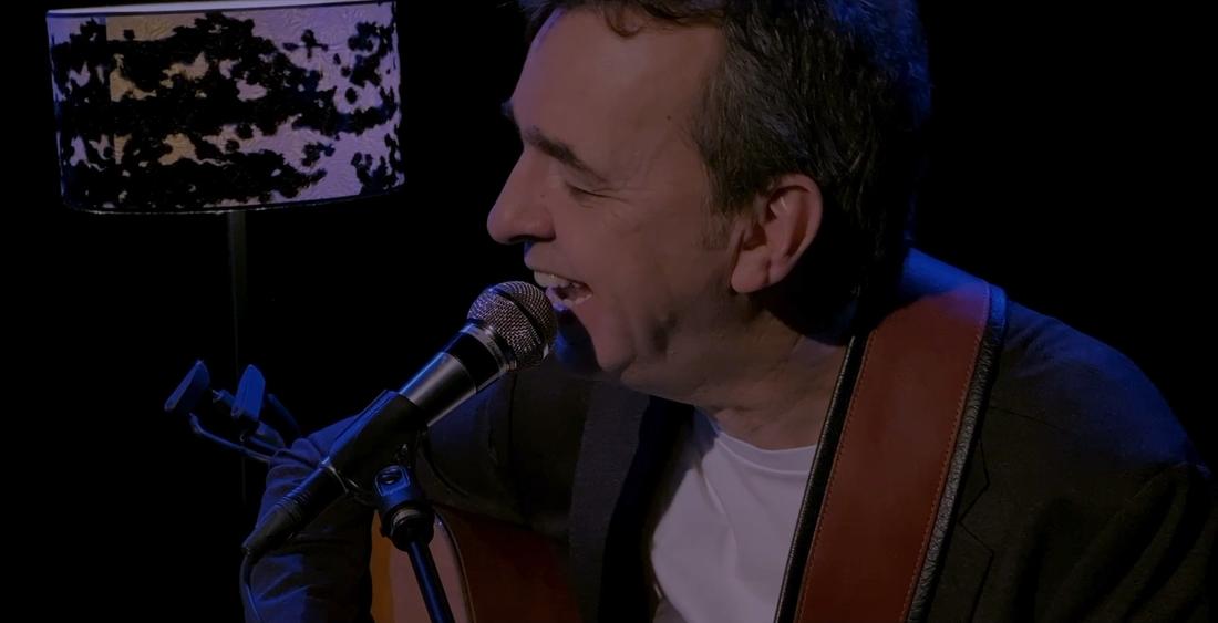 Gros plan sur le guitariste à la veste sombre qui chante