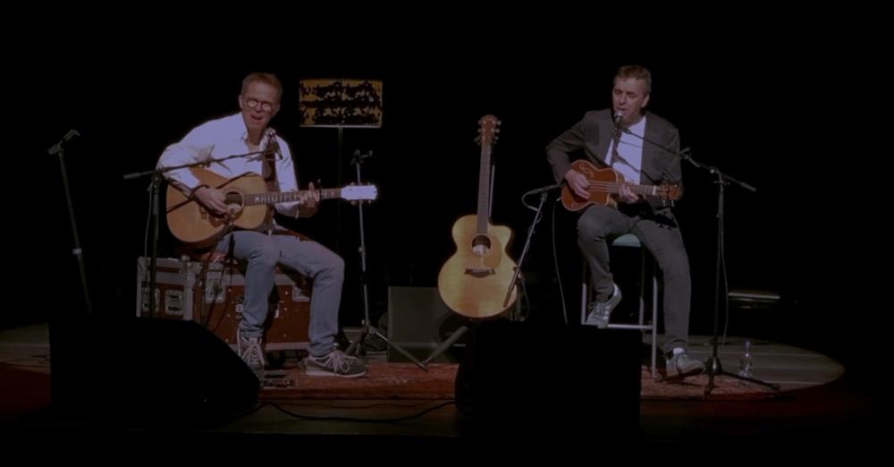 Le duo sur scène, vu de plus loin, éclairé par un projecteur